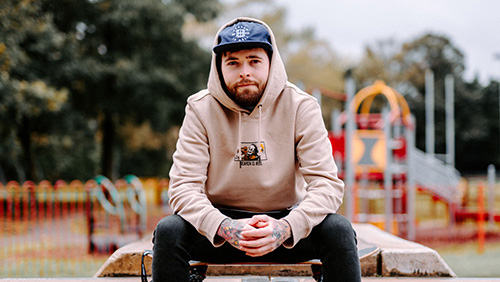 A photo of Zach Cundall sitting on a wall