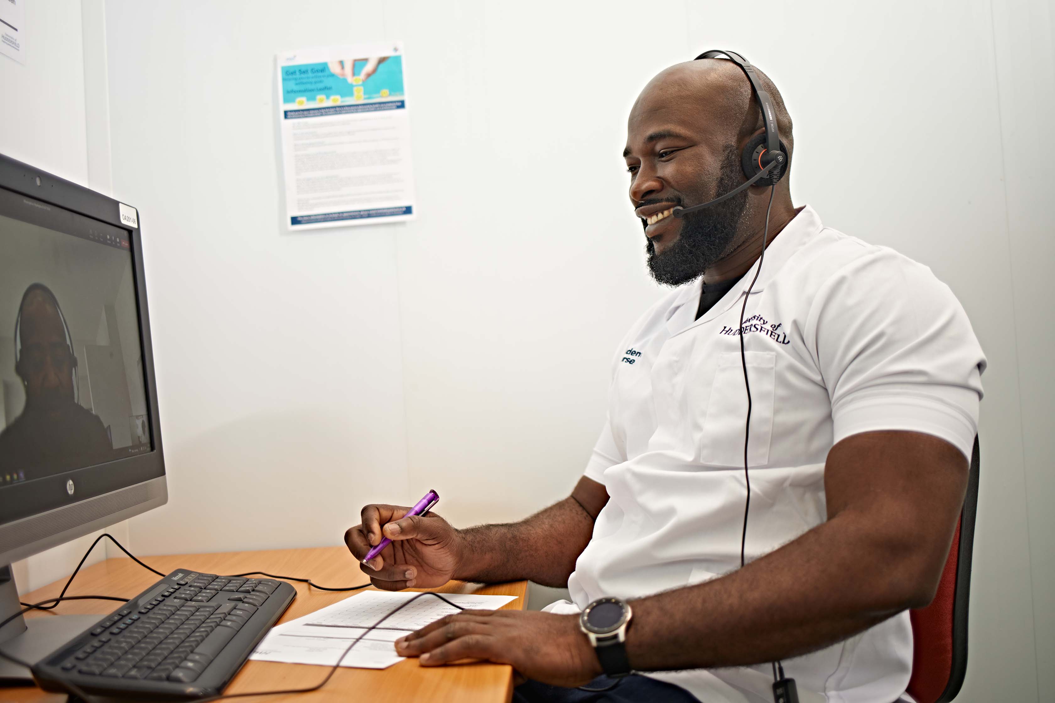 A University of Huddersfield nursing student is offering someone support over a video call; he is smiling