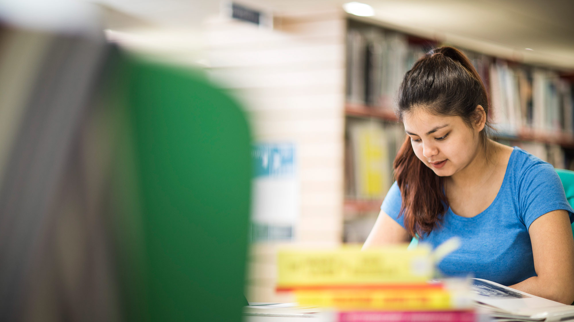A student reads books in the library.