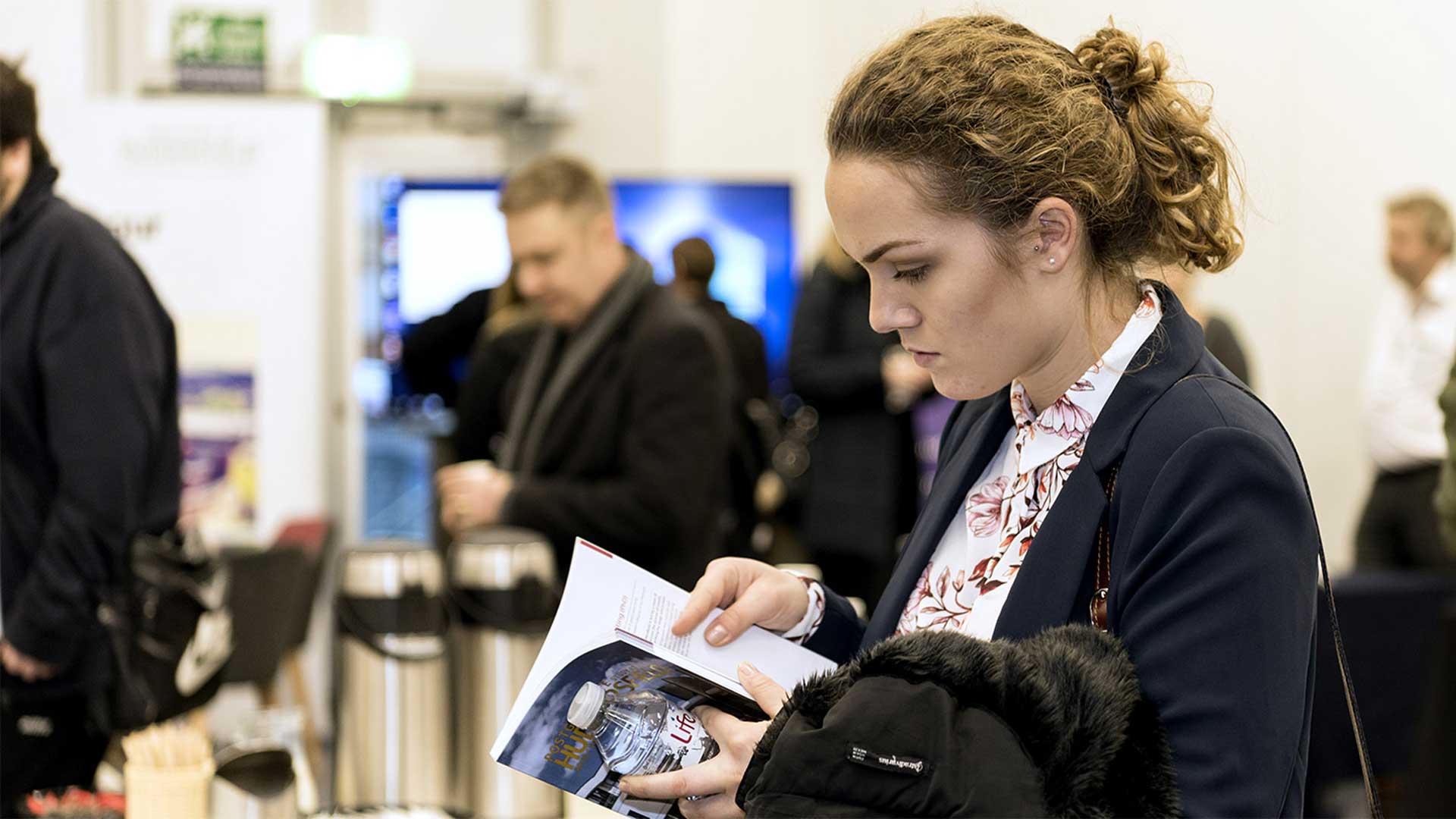 A potential postgraduate student at the PG Study Fair looking at the PG study prospectus.
