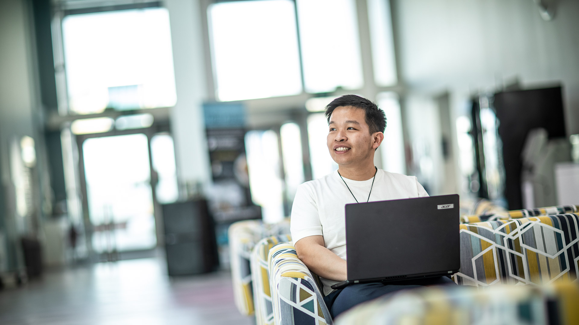 A student sat working on a laptop in a communal space.