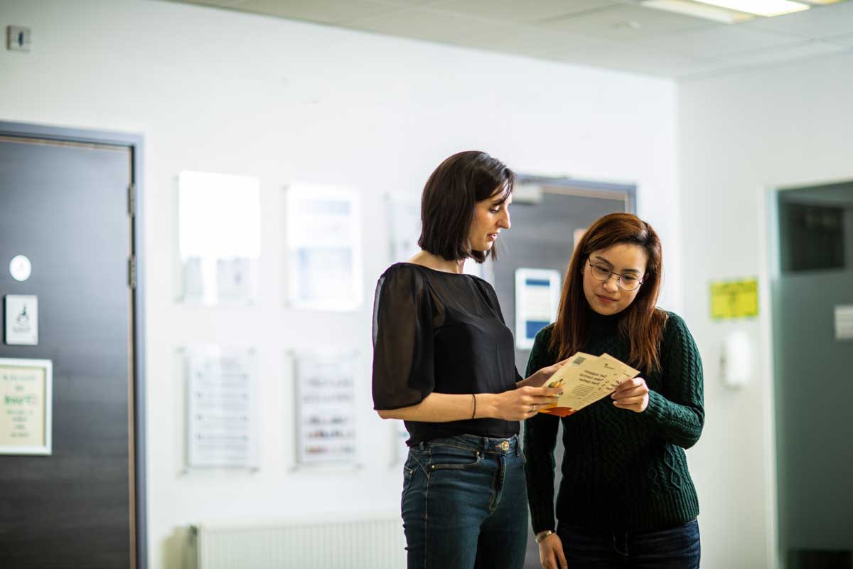 Two people talking with leaflets