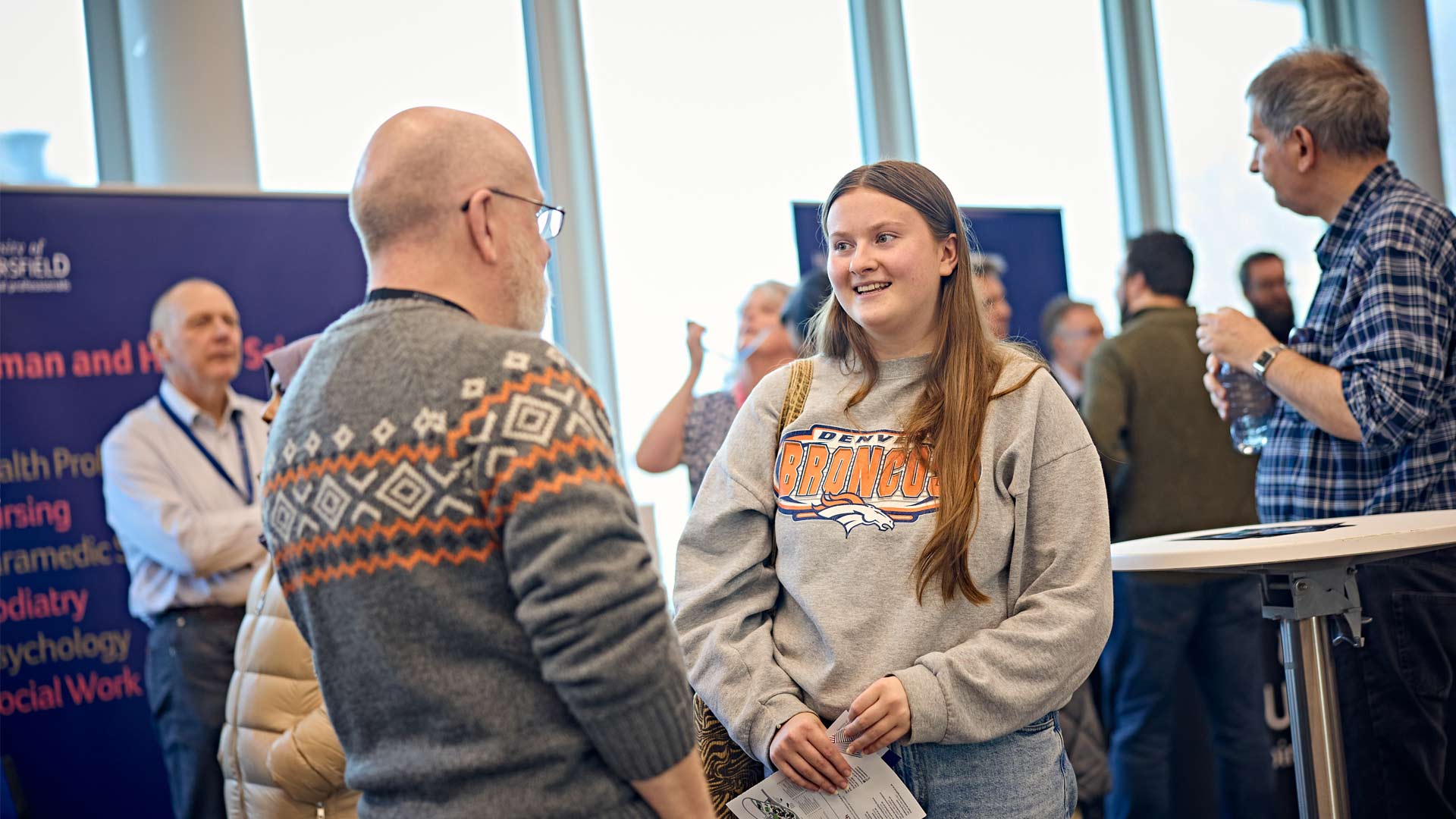Prospective postgraduate student smiling and speaking with staff member at Postgraduate Open Day